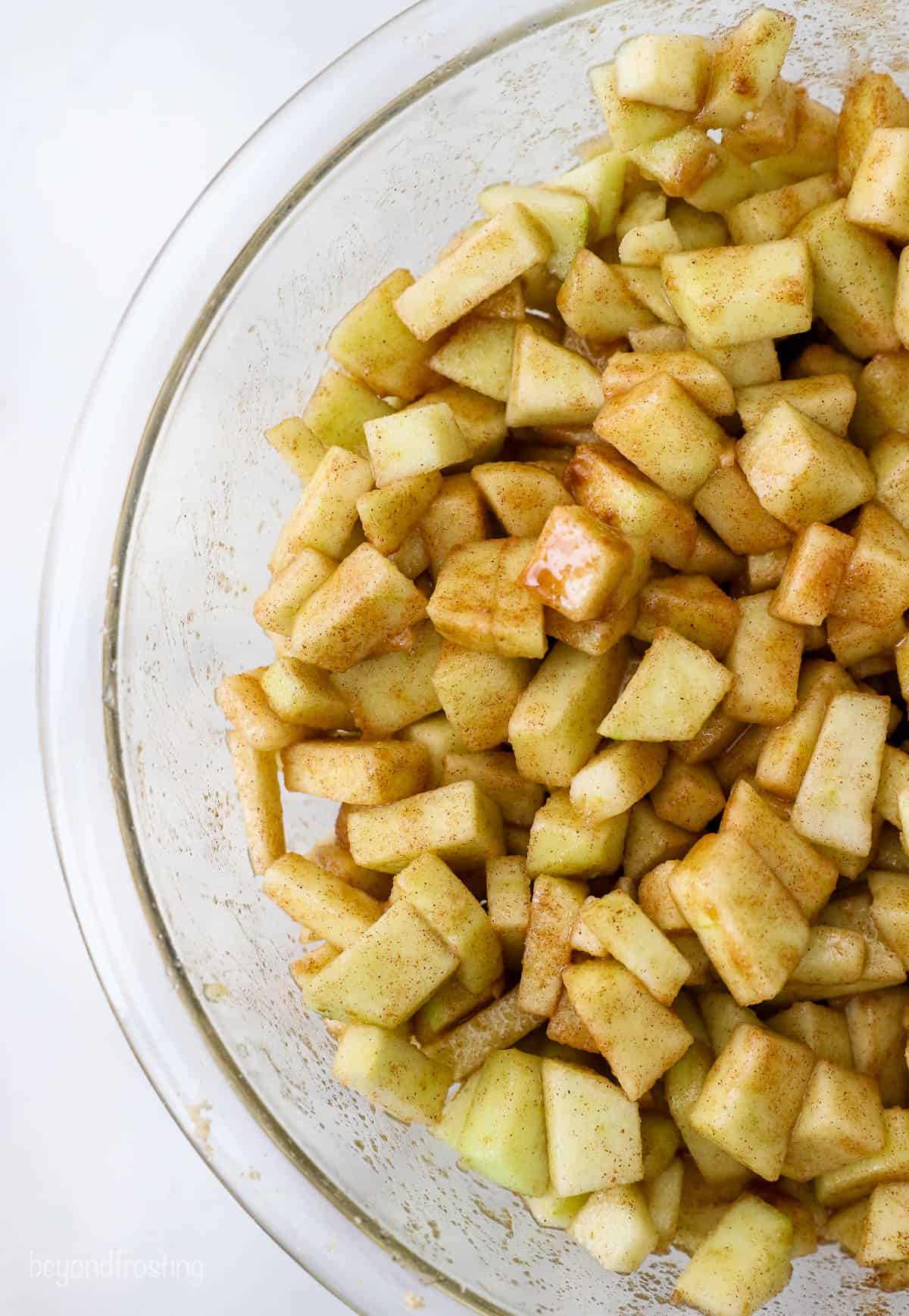 These mini apple pies are baked in a muffin tin and full of fall flavor! With gooey cinnamon apples, flaky pie crust, and a buttery crumble. Cinnamon apple pie filling in a glass mixing bowl.