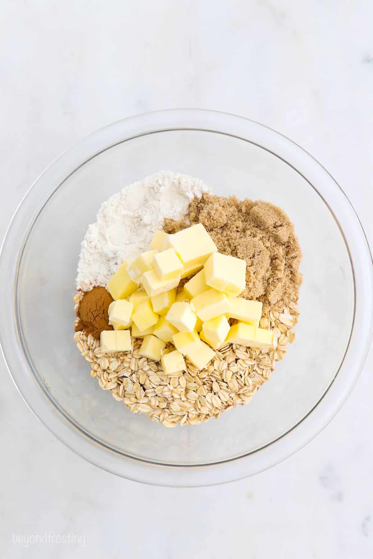 These mini apple pies are baked in a muffin tin and full of fall flavor! With gooey cinnamon apples, flaky pie crust, and a buttery crumble. Butter, oats, brown sugar, flour, and cinnamon combined in a glass bowl to make the crumble topping.
