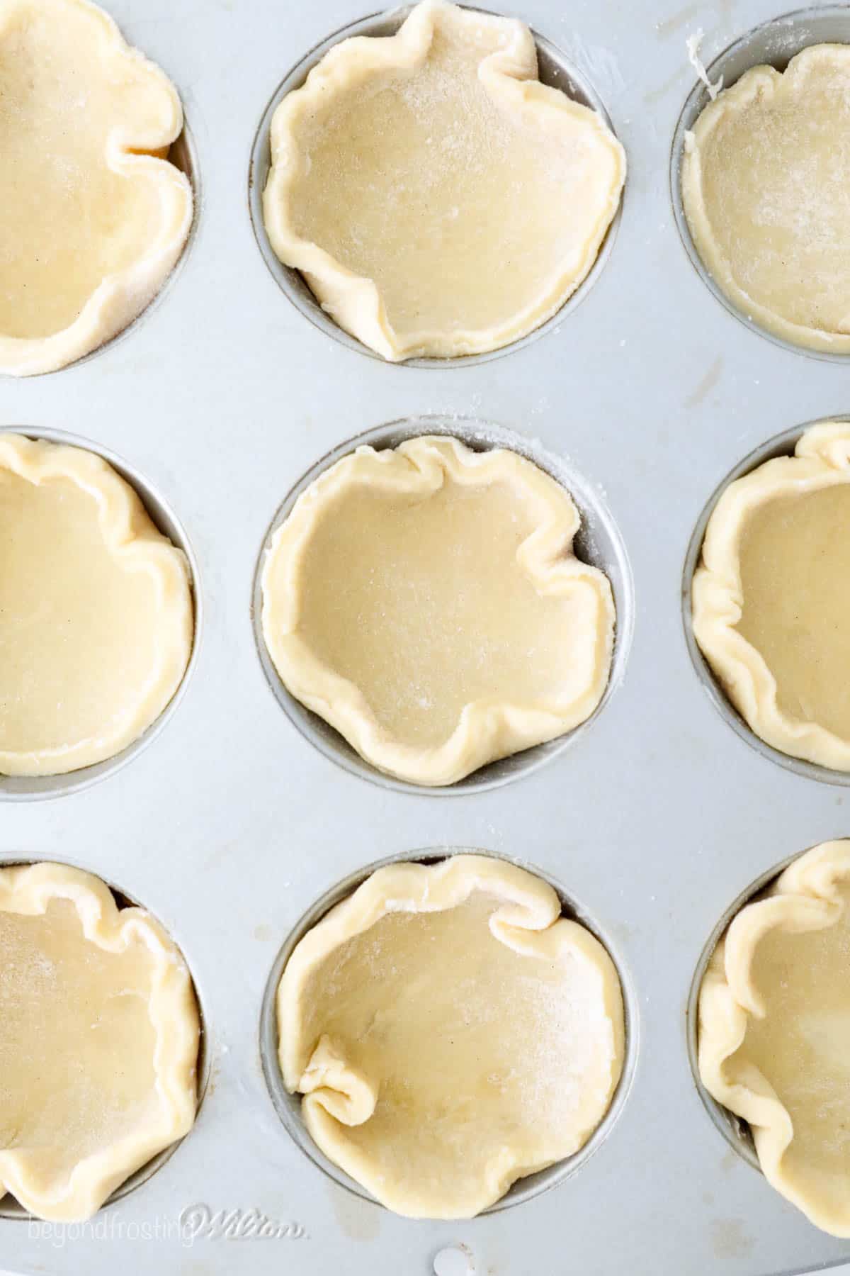 These mini apple pies are baked in a muffin tin and full of fall flavor! With gooey cinnamon apples, flaky pie crust, and a buttery crumble. Pie crusts pushed and shaped into the wells of a muffin pan.