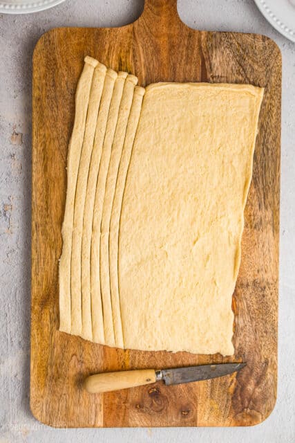 A Pillsbury crescent dough sheet with 6 thin strips cut off of it