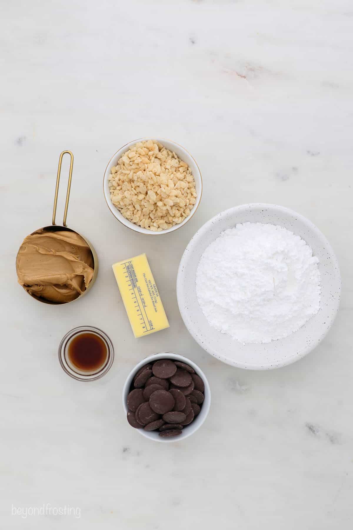 A bowl of powdered sugar, a stick of unsalted butter and the remaining truffle ingredients arranged on a countertop