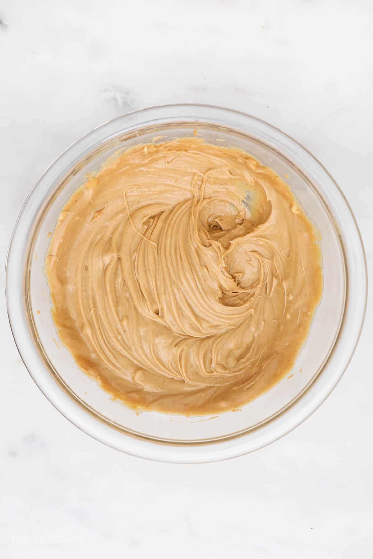 Smoothly combined butter and peanut butter inside of a glass mixing bowl