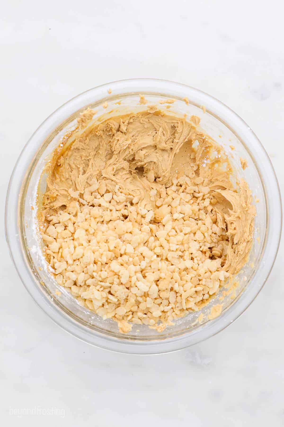 Peanut butter truffle dough in a bowl with Rice Krispies poured on top