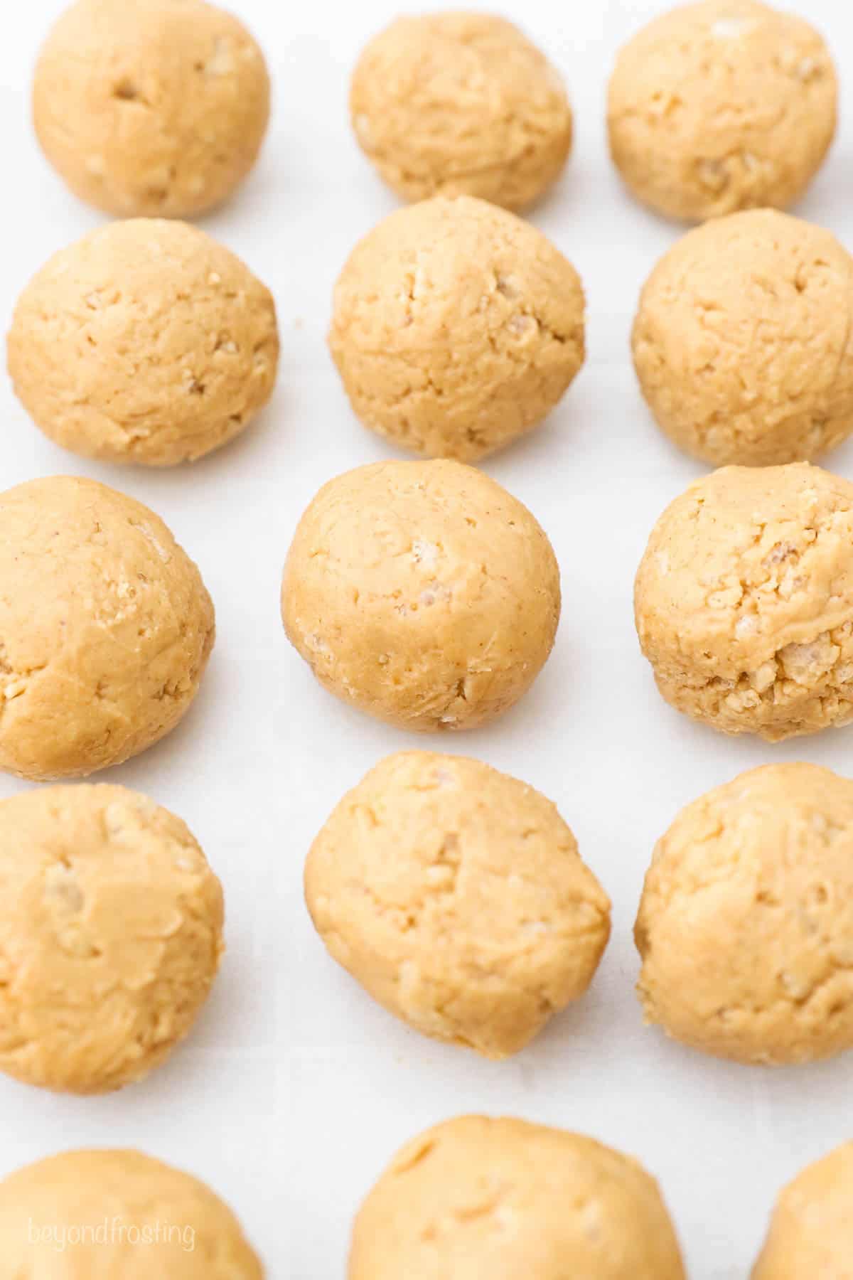 Fifteen uncoated peanut butter truffles on a baking sheet lined with parchment paper