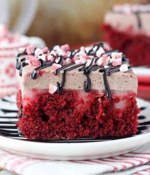 side view of a slice of red velvet poke cake on a white plate
