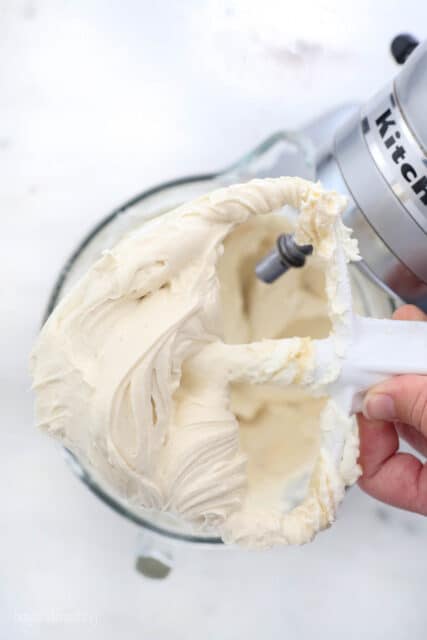 a beater attachment over a stand mixer with whipped cream cheese