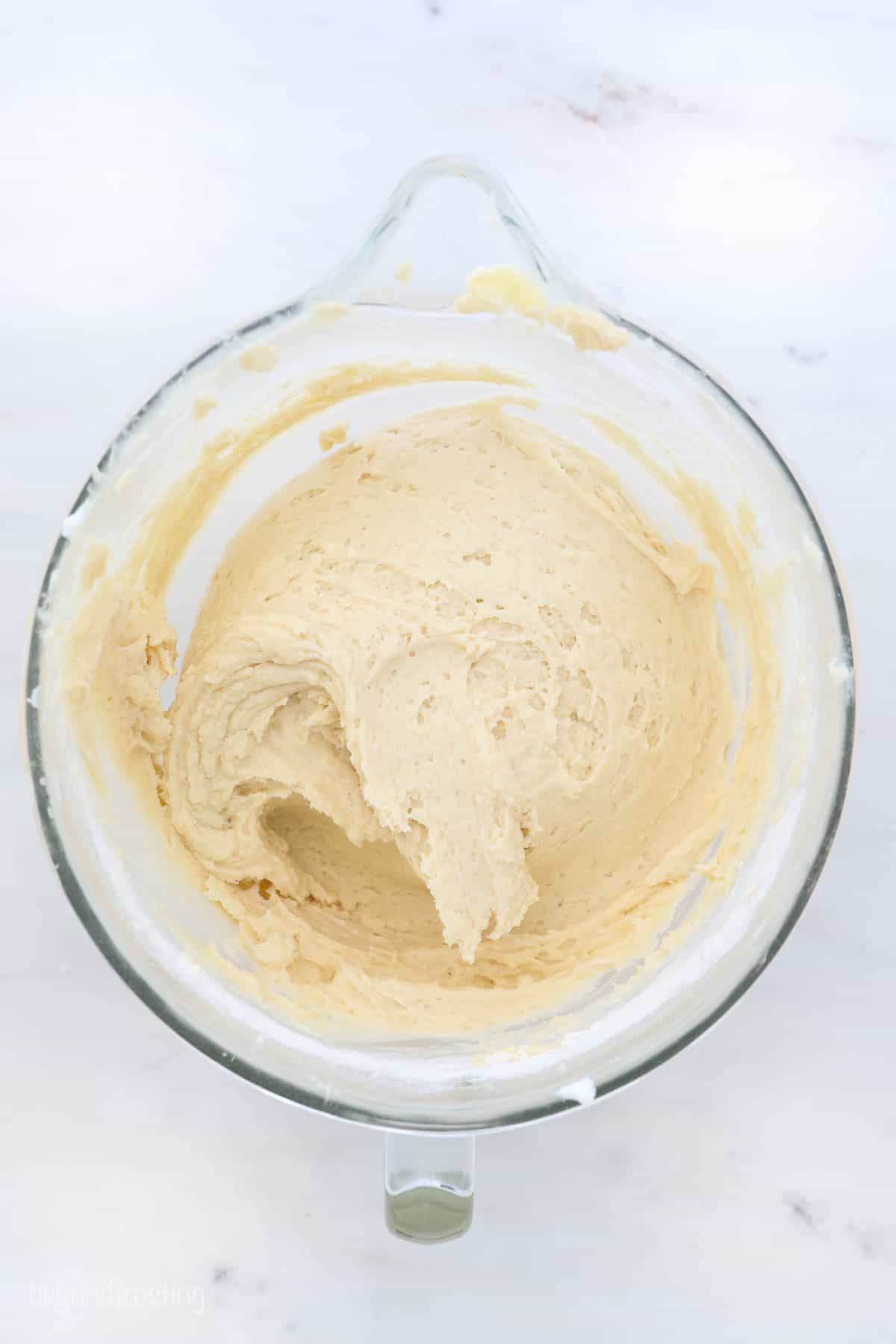 This classic coffee cake recipe is a thick, moist sour cream cake with a crumbly, buttery cinnamon streusel. Enjoy a slice with coffee or tea! A glass mixing bowl with cake batter.