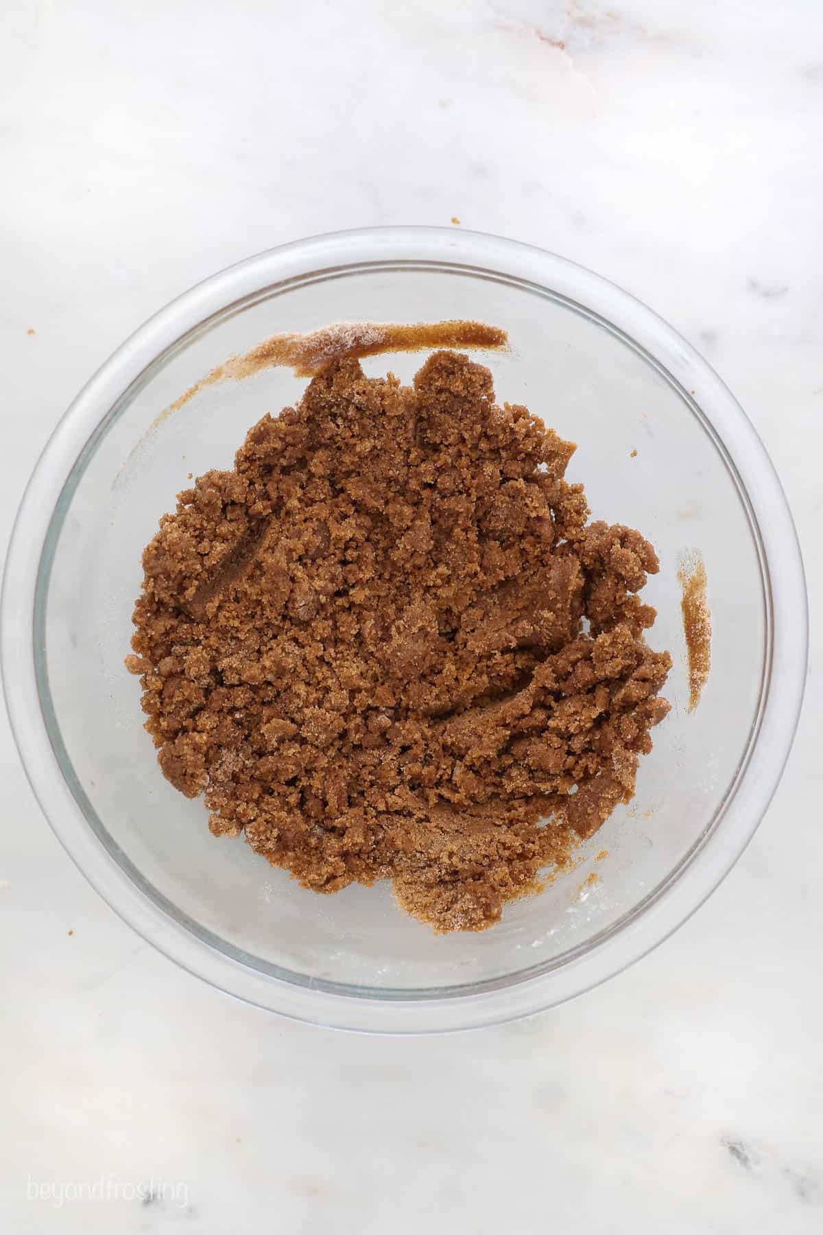 This classic coffee cake recipe is a thick, moist sour cream cake with a crumbly, buttery cinnamon streusel. Enjoy a slice with coffee or tea! A glass mixing bowl with streusel topping.