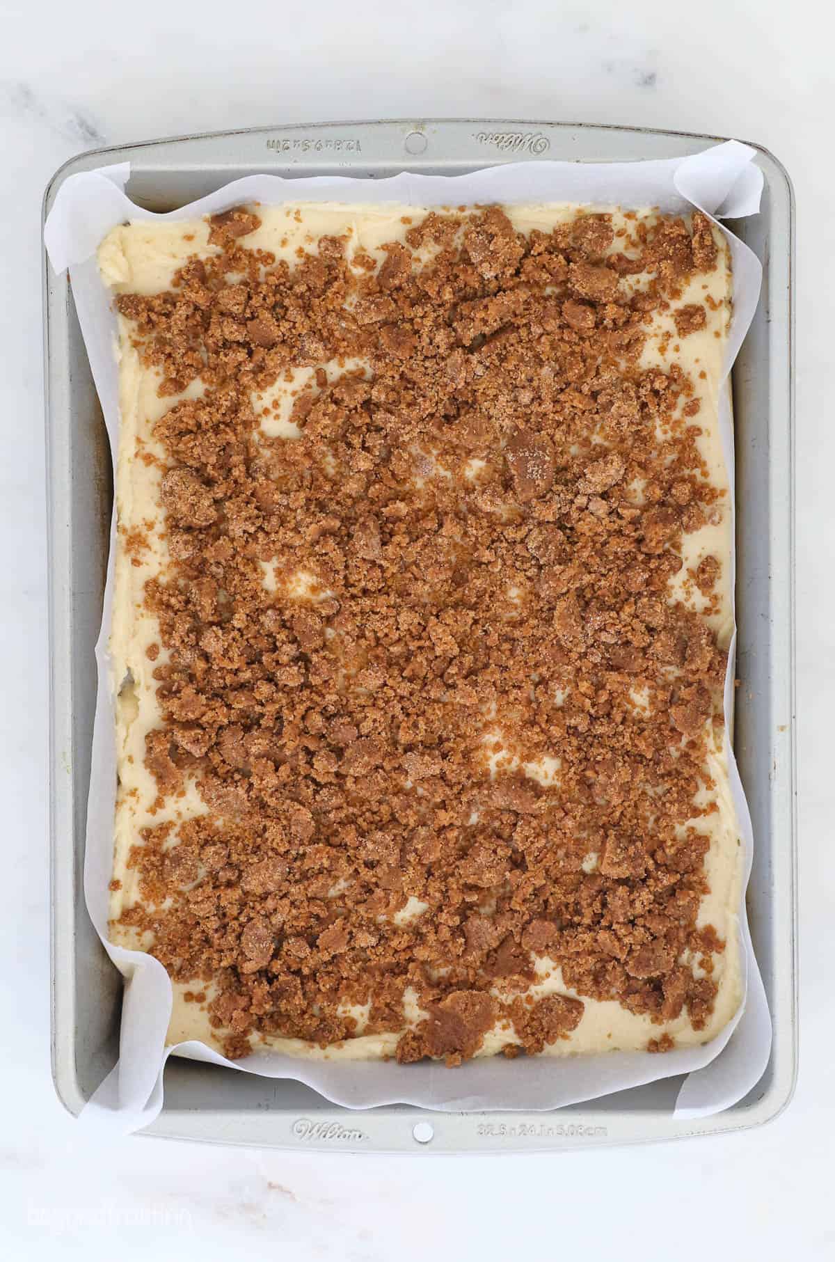This classic coffee cake recipe is a thick, moist sour cream cake with a crumbly, buttery cinnamon streusel. Enjoy a slice with coffee or tea! Streusel topping sprinkled on top of coffee cake batter in a baking pan.