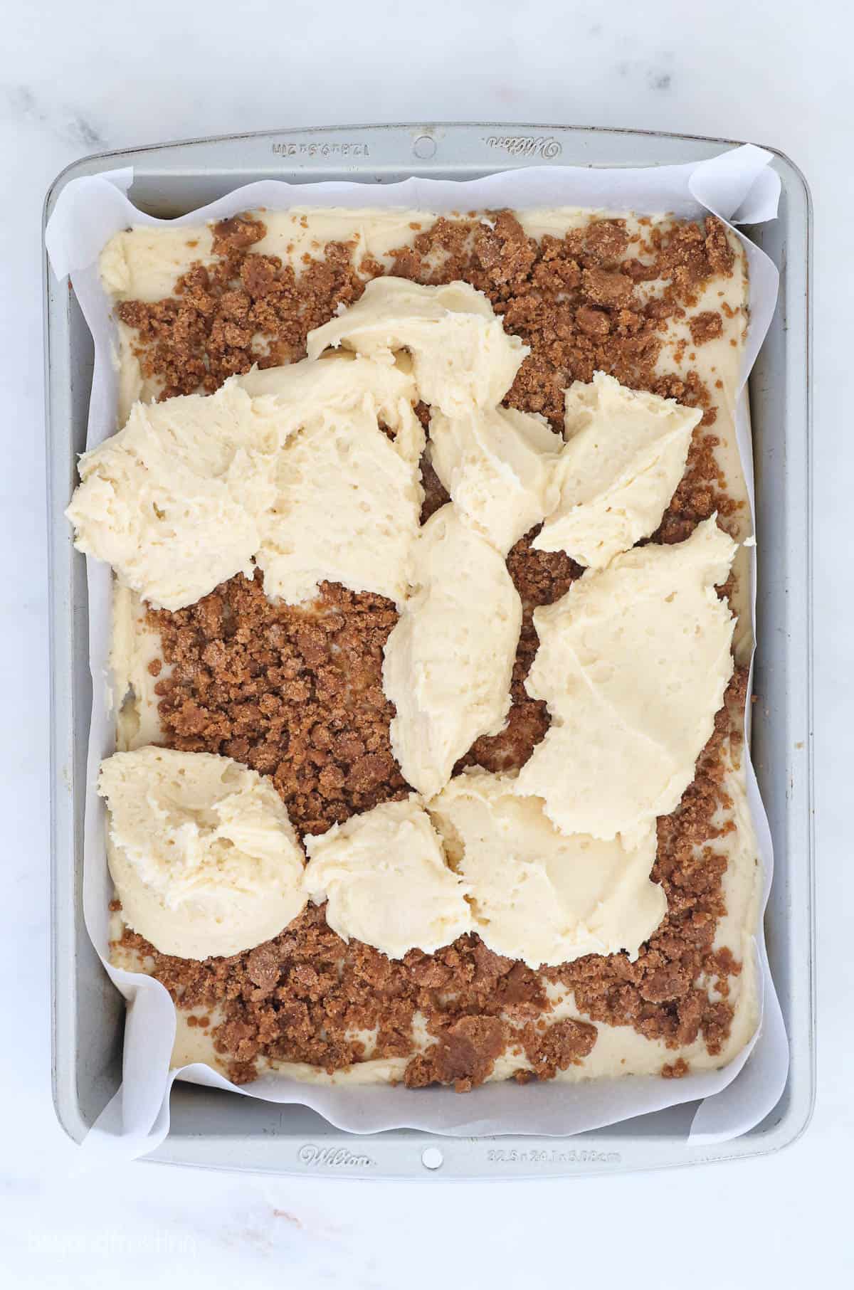 This classic coffee cake recipe is a thick, moist sour cream cake with a crumbly, buttery cinnamon streusel. Enjoy a slice with coffee or tea! Cake batter added on top of the streusel layer in a baking pan.