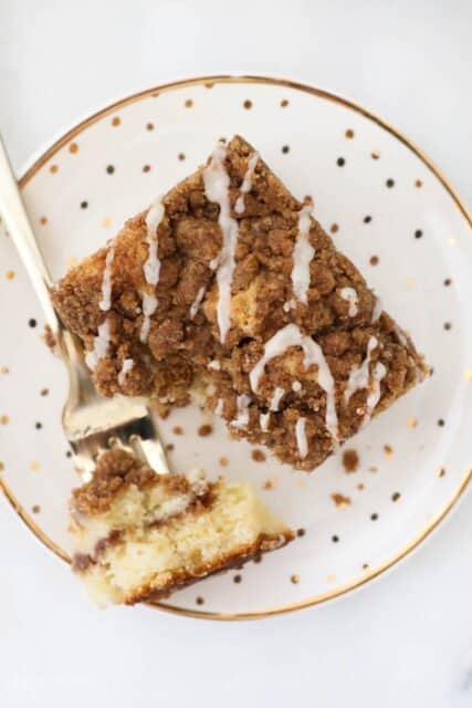 an overhead view of a slice of coffee cake with a bite removed, sitting on a gold polka dot plate
