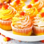 A close up of a candy corn cupcake on a white rimmed plate