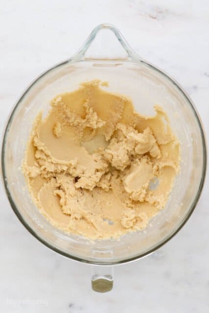 Creamed butter, granulated sugar and brown sugar in a glass container on top of a marble counter