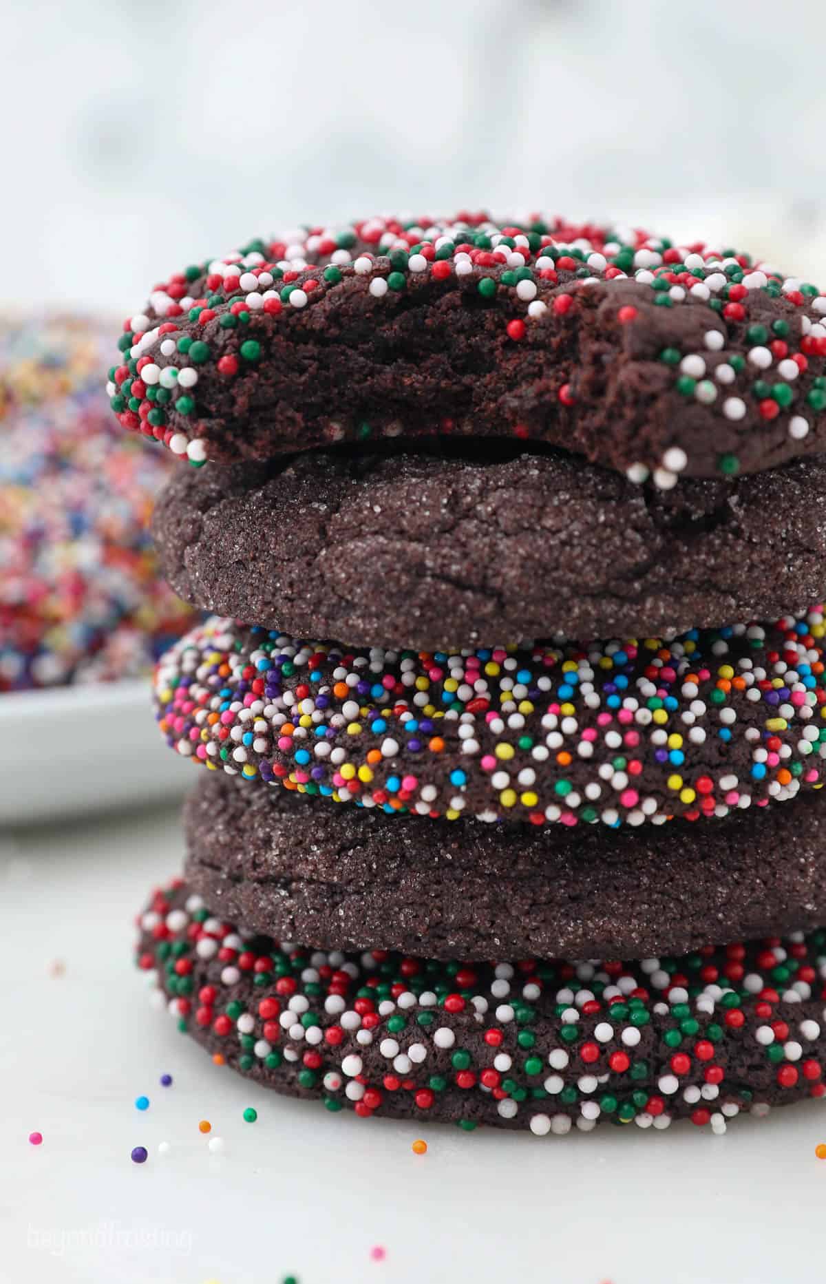 A stack of five sugar cookies with every other cookie covered in nonpareil sprinkles