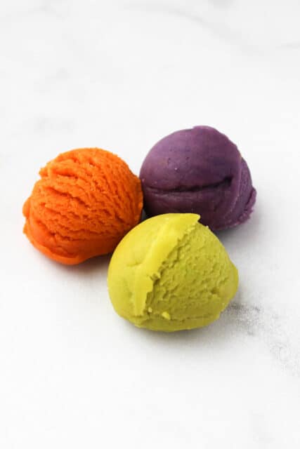three small scoops of sugar cookie dough, orange, purple and green