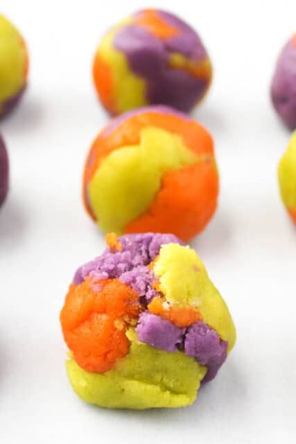 orange, purple and green sugar cookie dough rolled together into balls