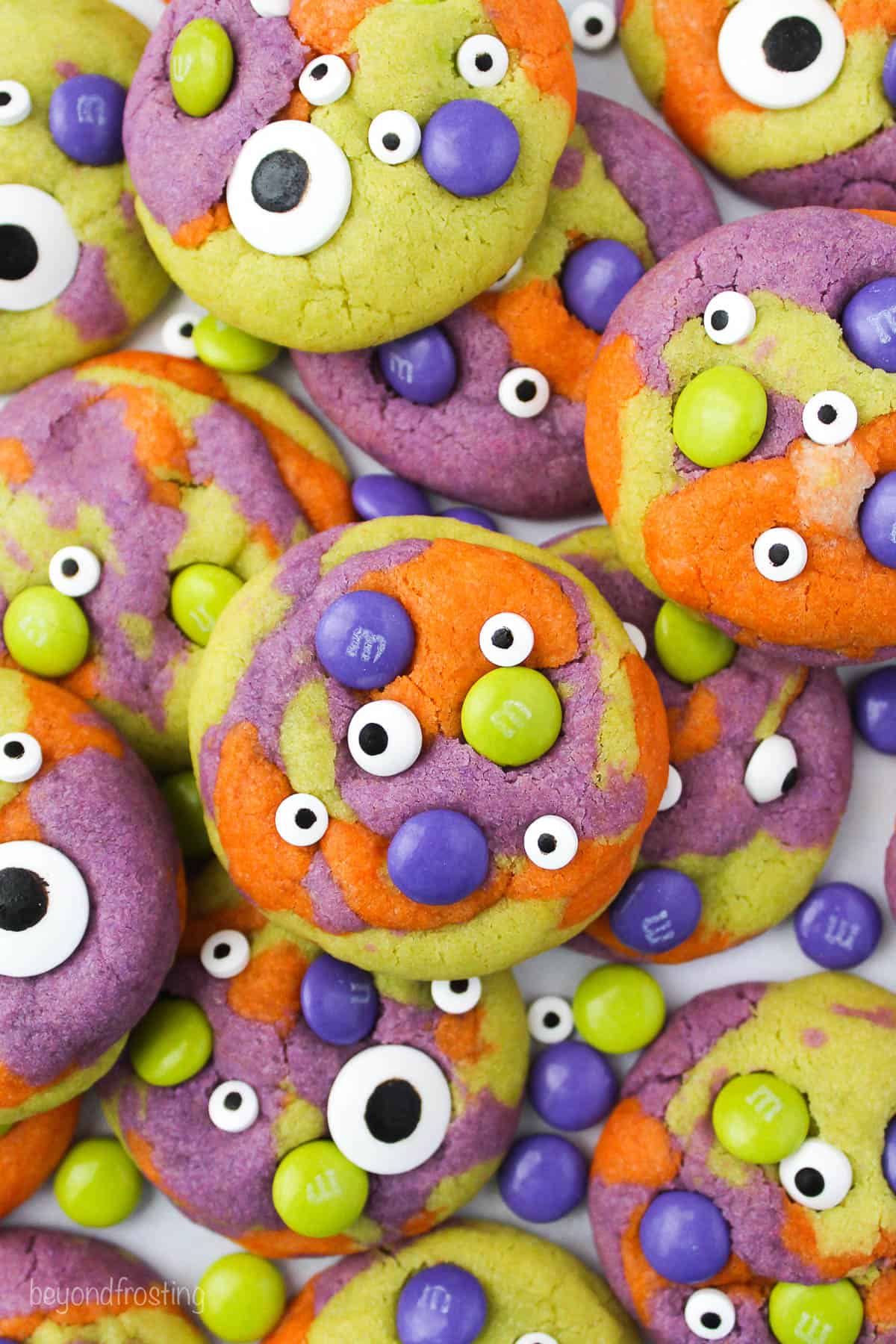 overhead shot of purple, orange and green tye dye cookies with M&Ms and googly eyes.