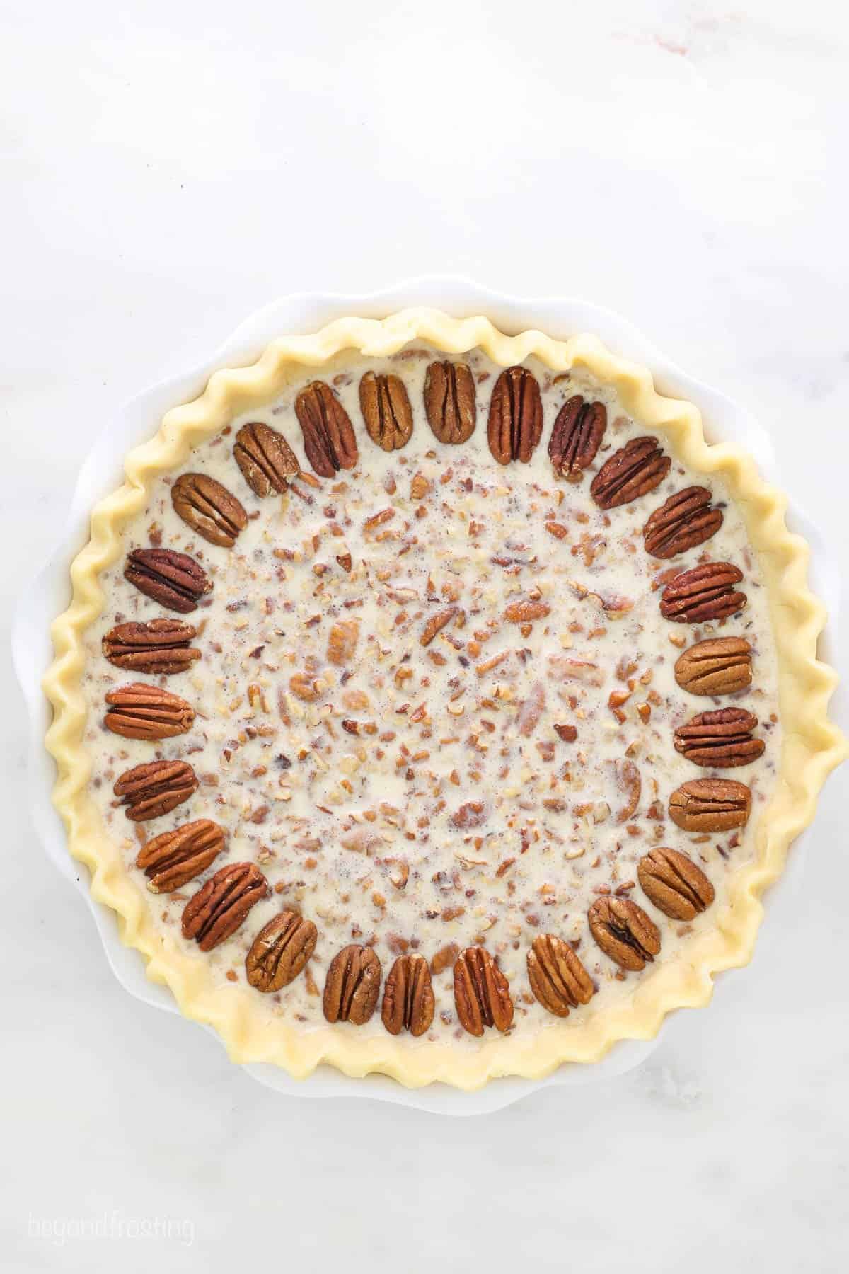 A homemade pie crust with the unbaked Kahlua pecan filling inside and a ring of halved pecans around the top edge