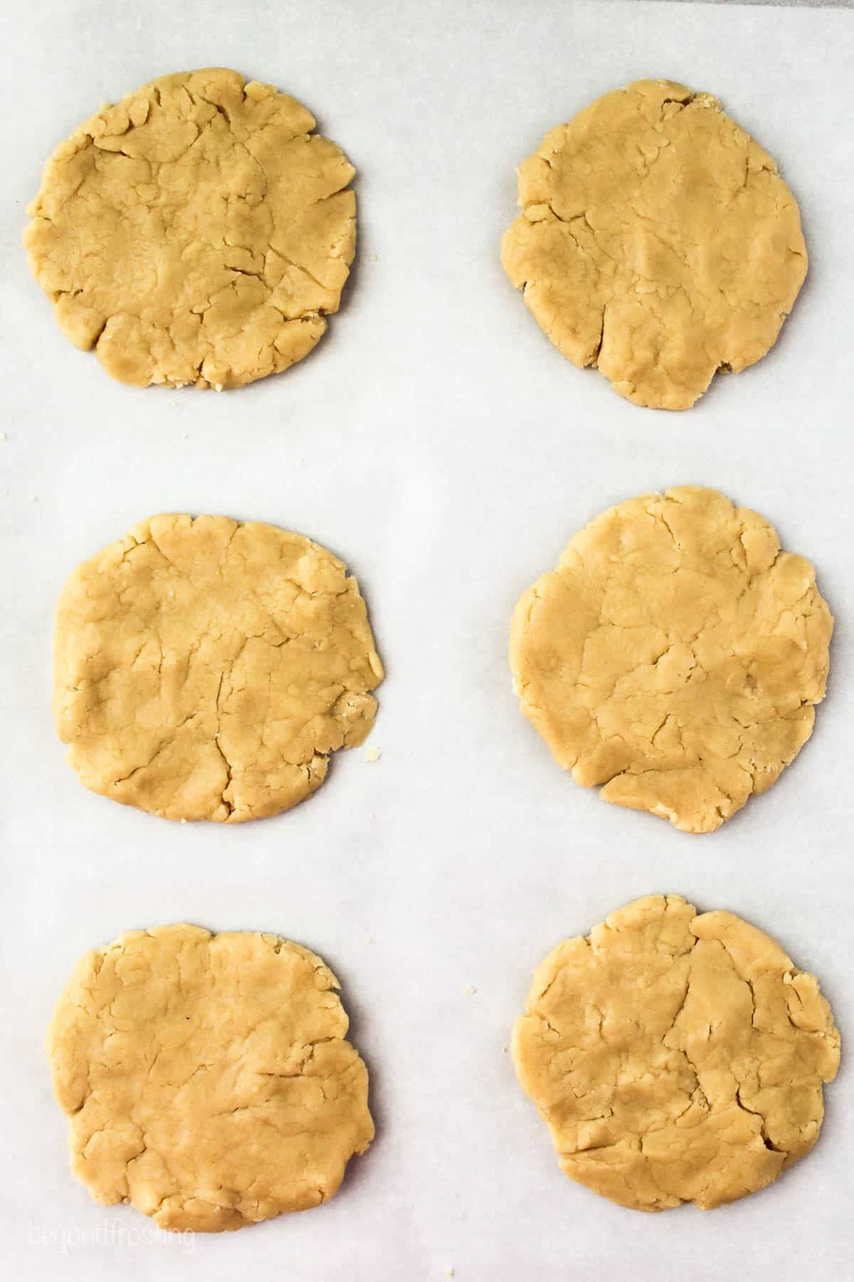 six sugar cookies on a lined baking sheet overhead