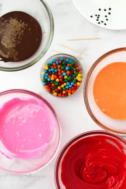 bowls of melted chocolate, colored candy melts, and sprinkles for decorating cookies