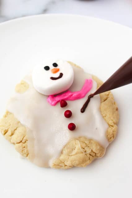 arm being piped onto melted snowman cookie