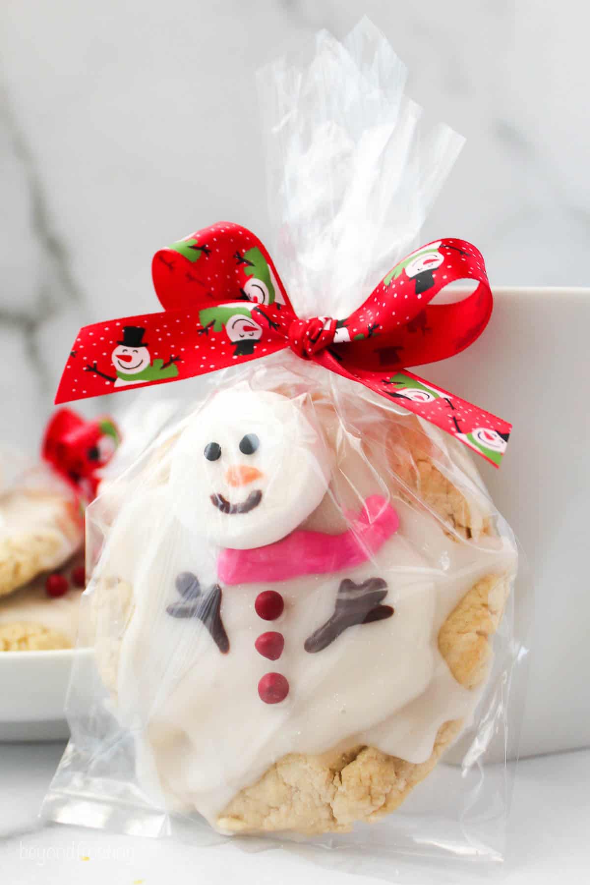 melted snowman cookie in a plastic gift bag tied with a red ribbon