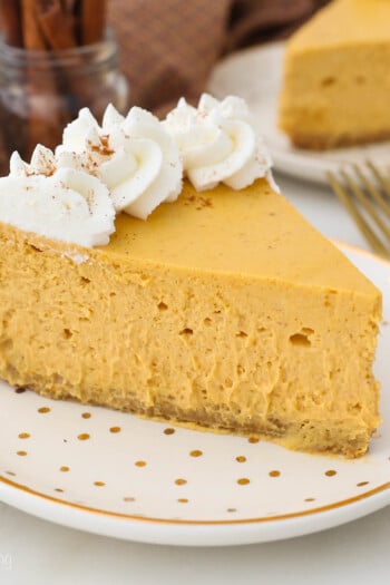 A gold polka dot plate with a slice of pumpkin cheesecake garnished with whipped cream