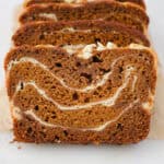 A close up shot of sliced pumpkin bread with swirls of cream cheese filling
