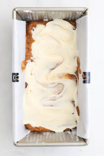 overhead shot of a loaf pan with pumpkin bread swirled with cream cheese filling