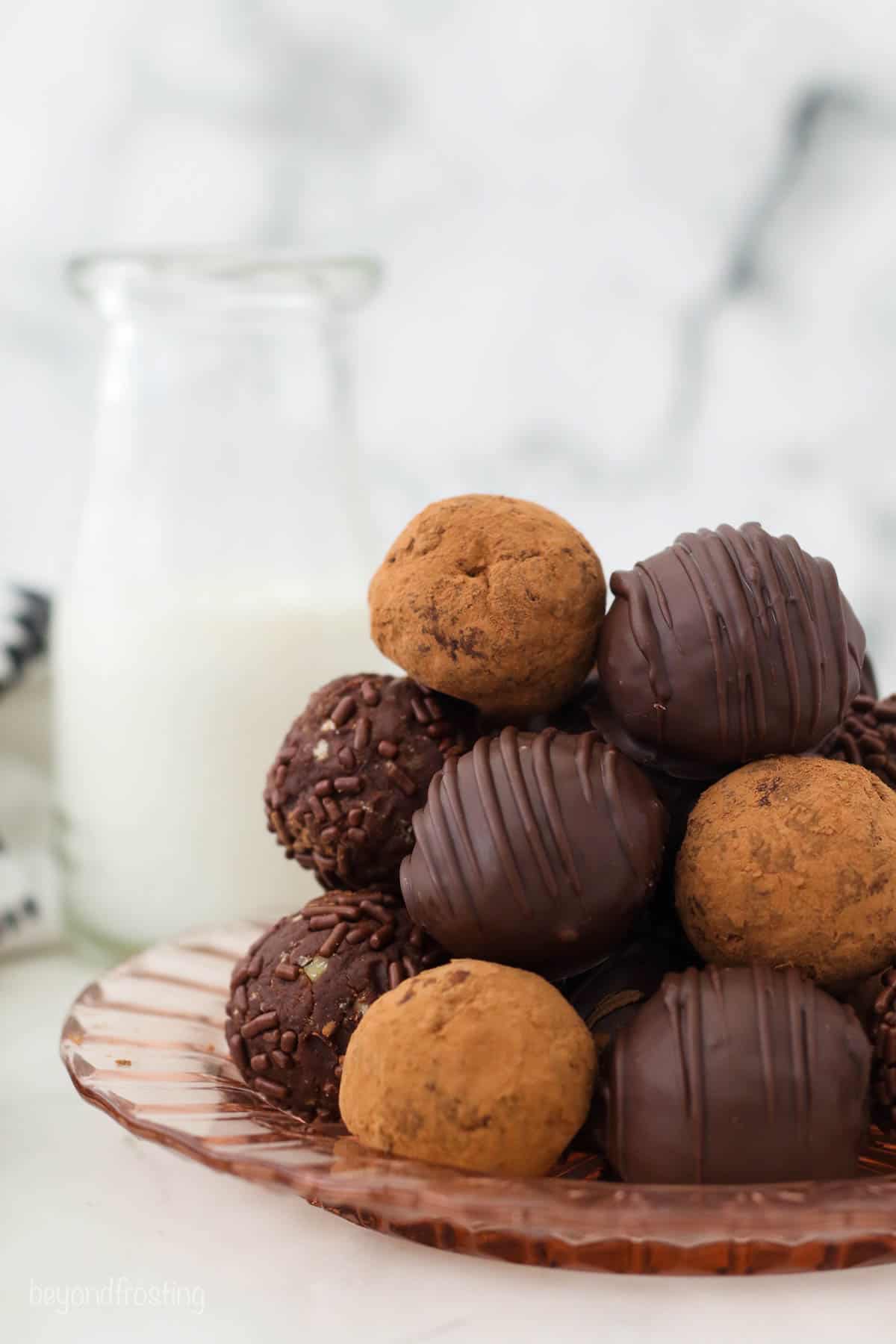 A glass plate piled high with rum balls decorated in various ways