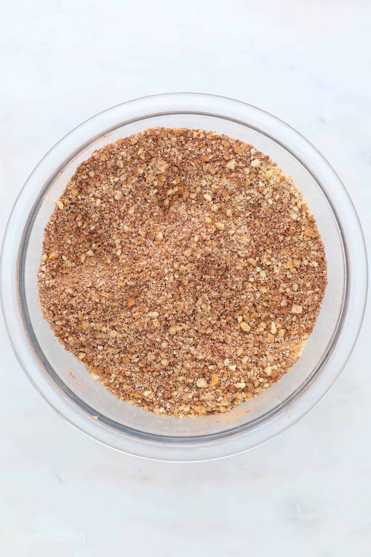 A clear bowl containing crushed Nilla wafers and finely chopped pecans