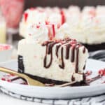 A sliced peppermint cheesecake on a white plate with dripping chocolate drizzle