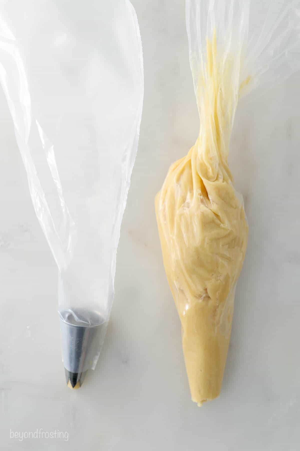 A piping bag fitted with a large open star piping tip beside a second bag containing a cup of dough