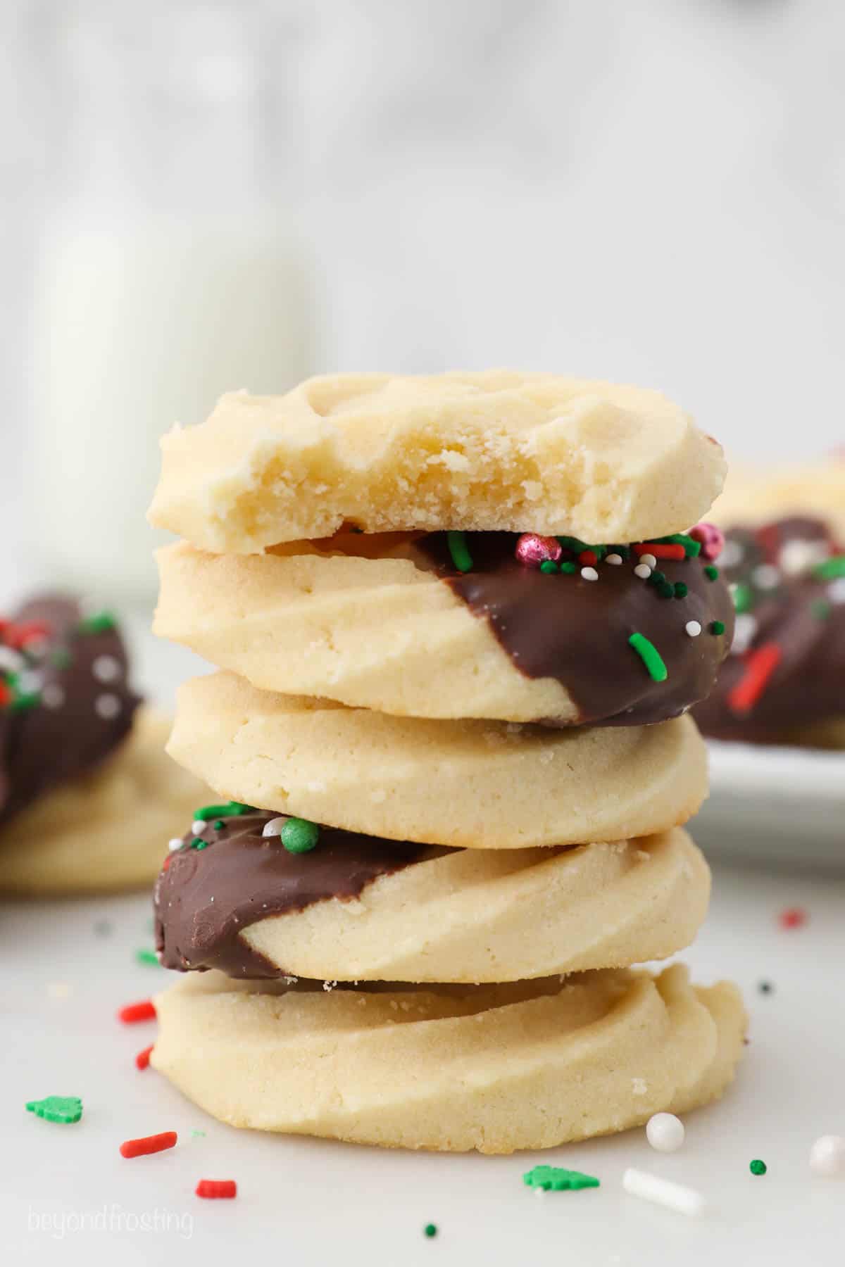 A stack of five butter cookies, two of which are decorated with chocolate and sprinkles