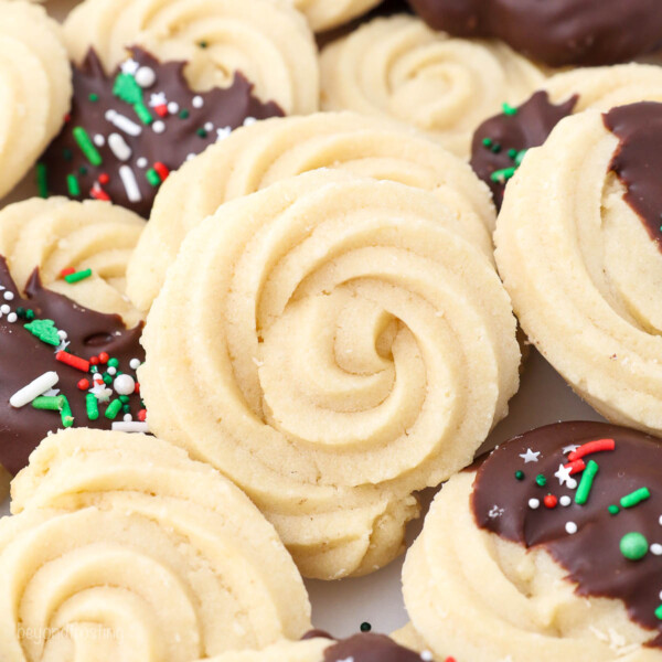 A plain swirly butter cookie on a countertop surrounded by chocolate-dipped butter cookies