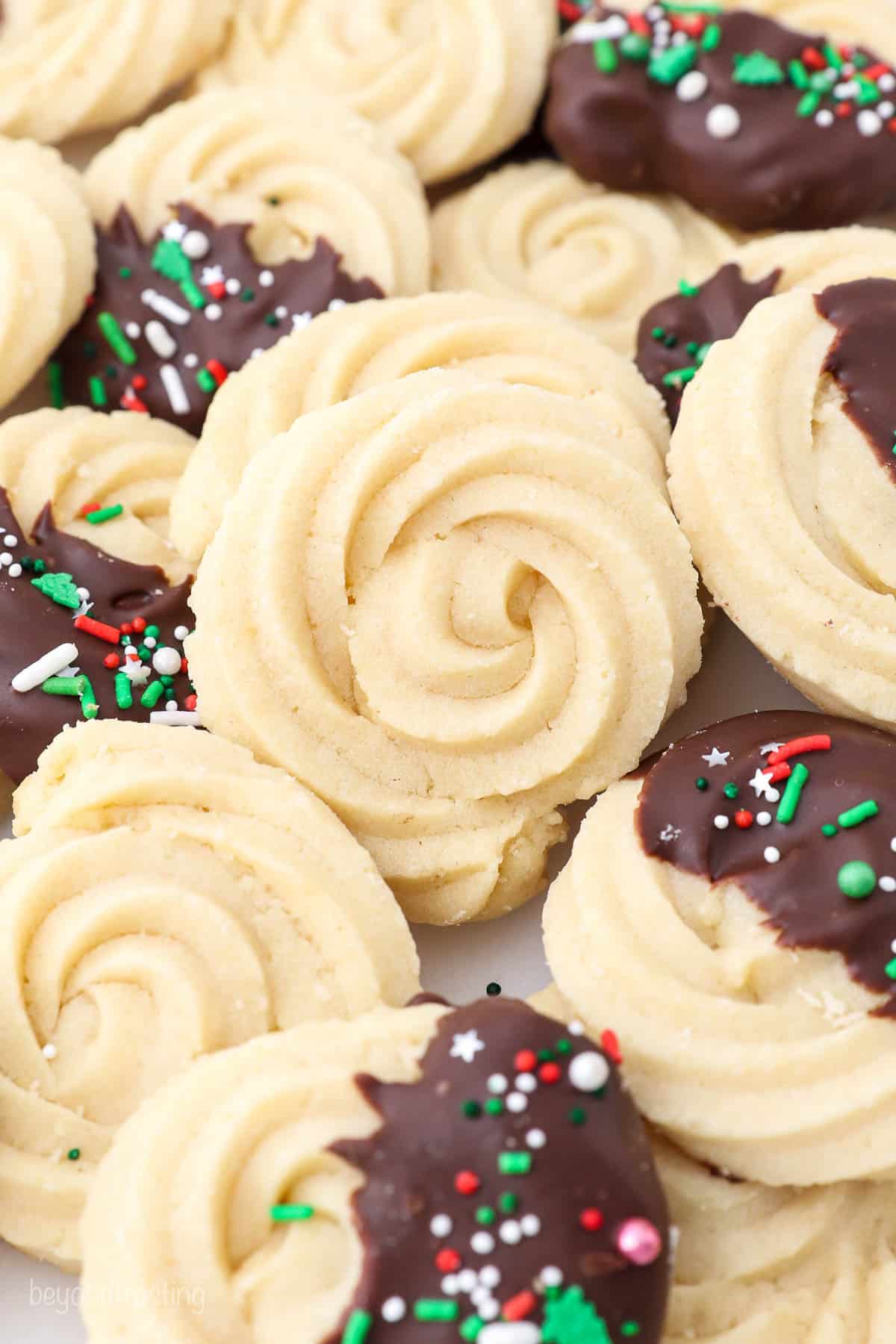 A close-up shot of homemade butter cookies with dark chocolate and sprinkles decorating about half of them