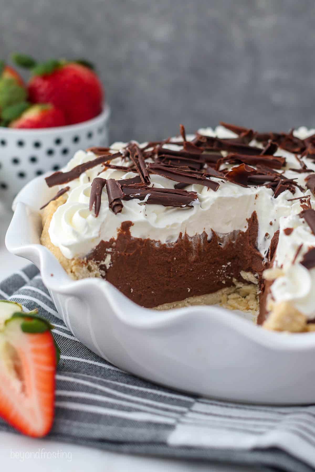 A white pie plate filled with chocolate pudding, topped with whipped cream and chocolate shavings