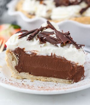 A close up of a sliced chocolate pie on a white plate dusted with cocoa powder