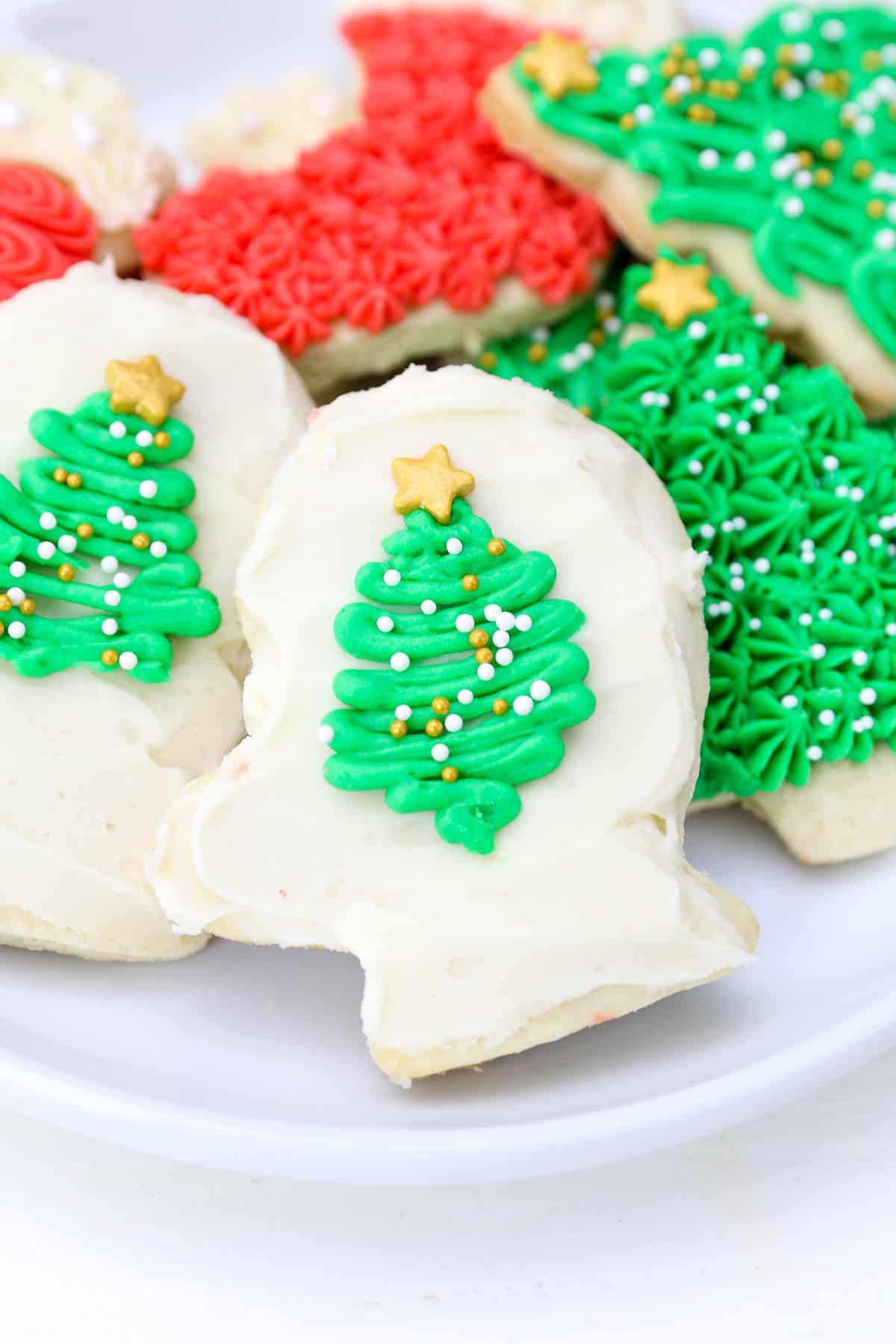 A glove shaped sugar cookie decorated with white frosting and a Christmas tree