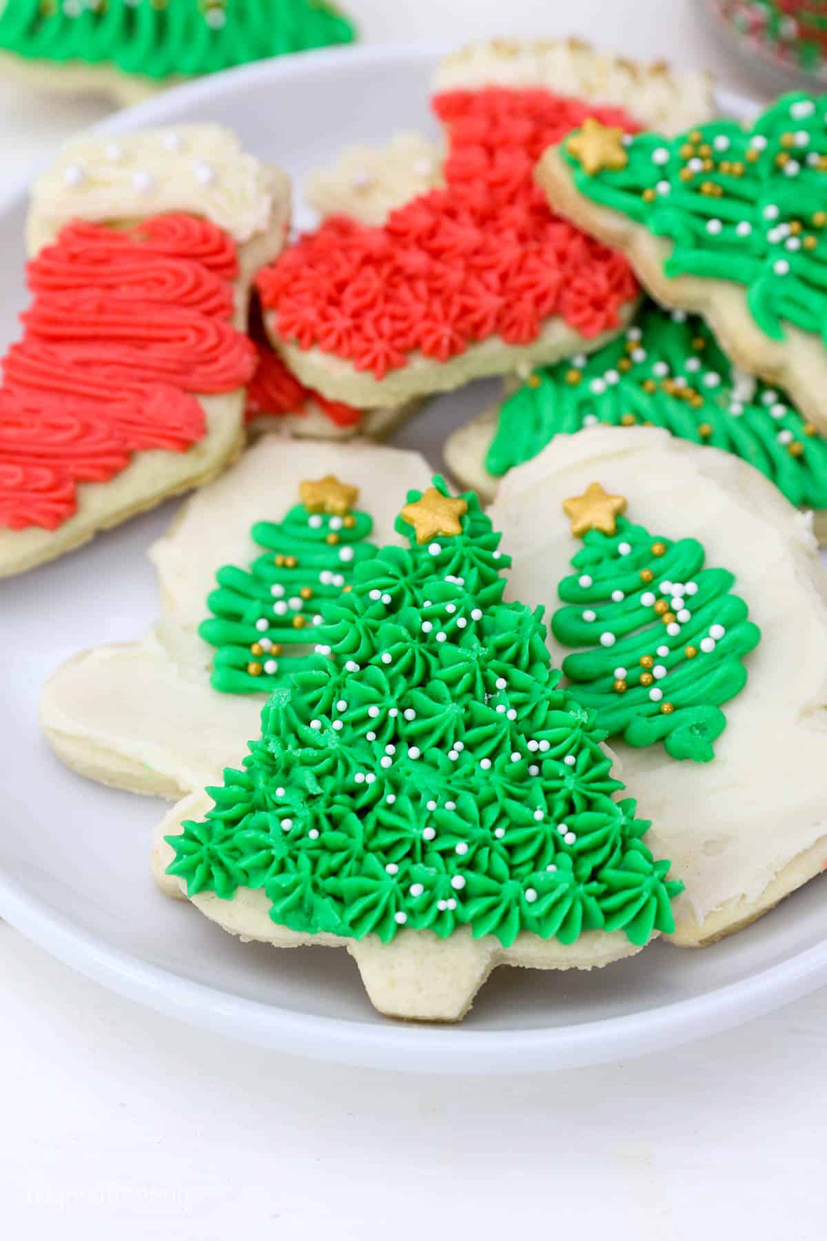 Decorated Christmas cookies with buttercream and sprinkles on a white plate