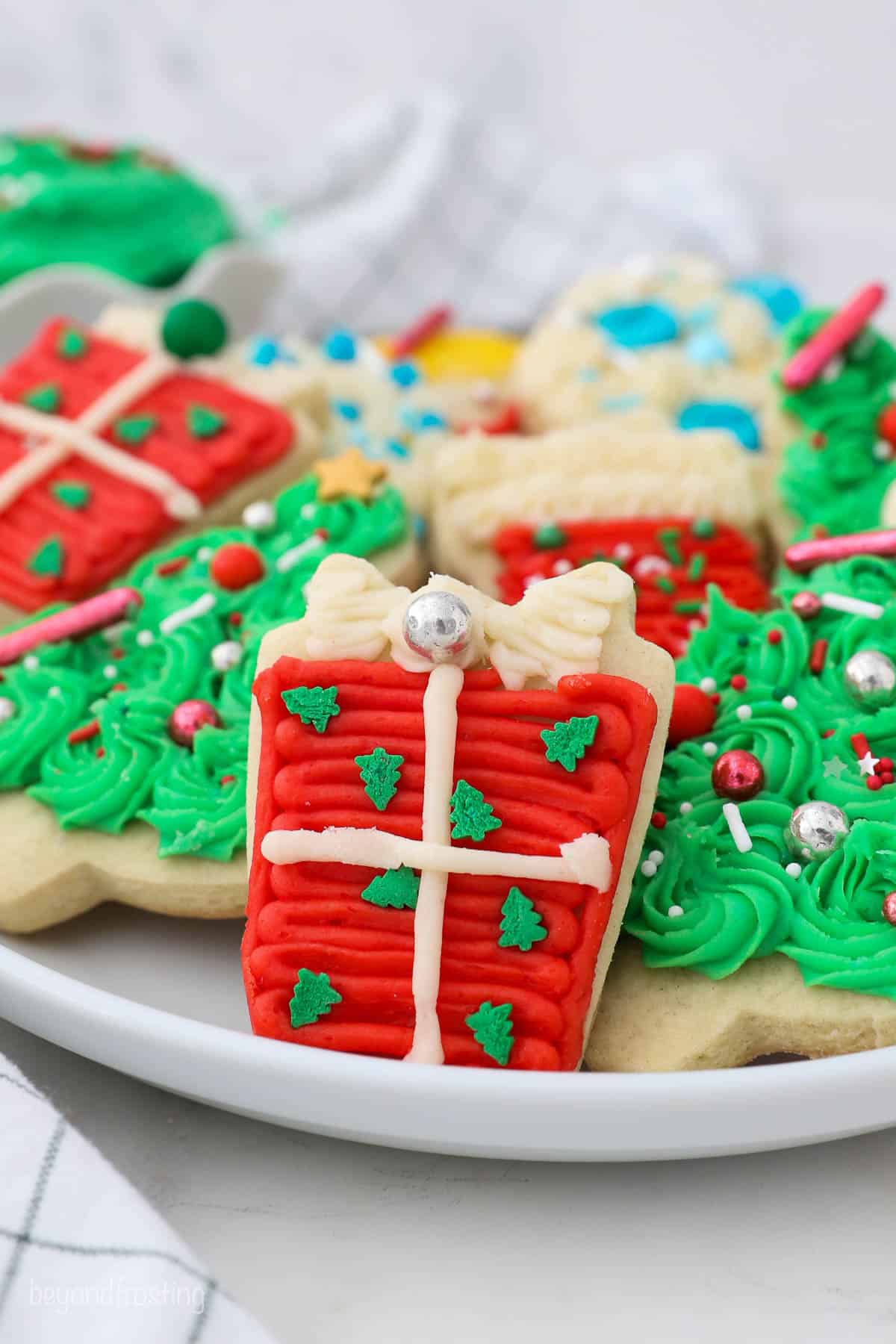 A decorated present Christmas cookie with red and white buttercream