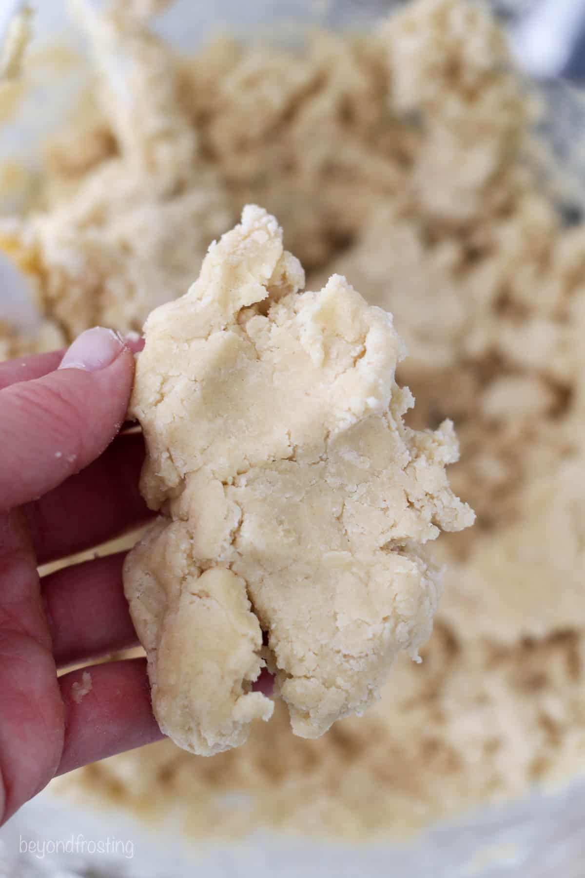 a hand pressing some cookie dough together