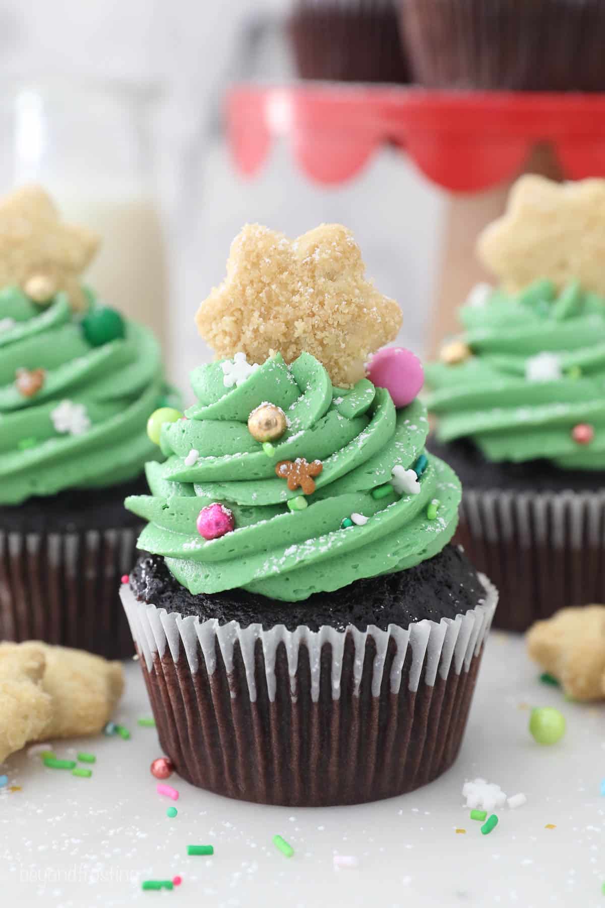 A chocolate cupcake decorated with green frosting, sprinkles and a star cookie top