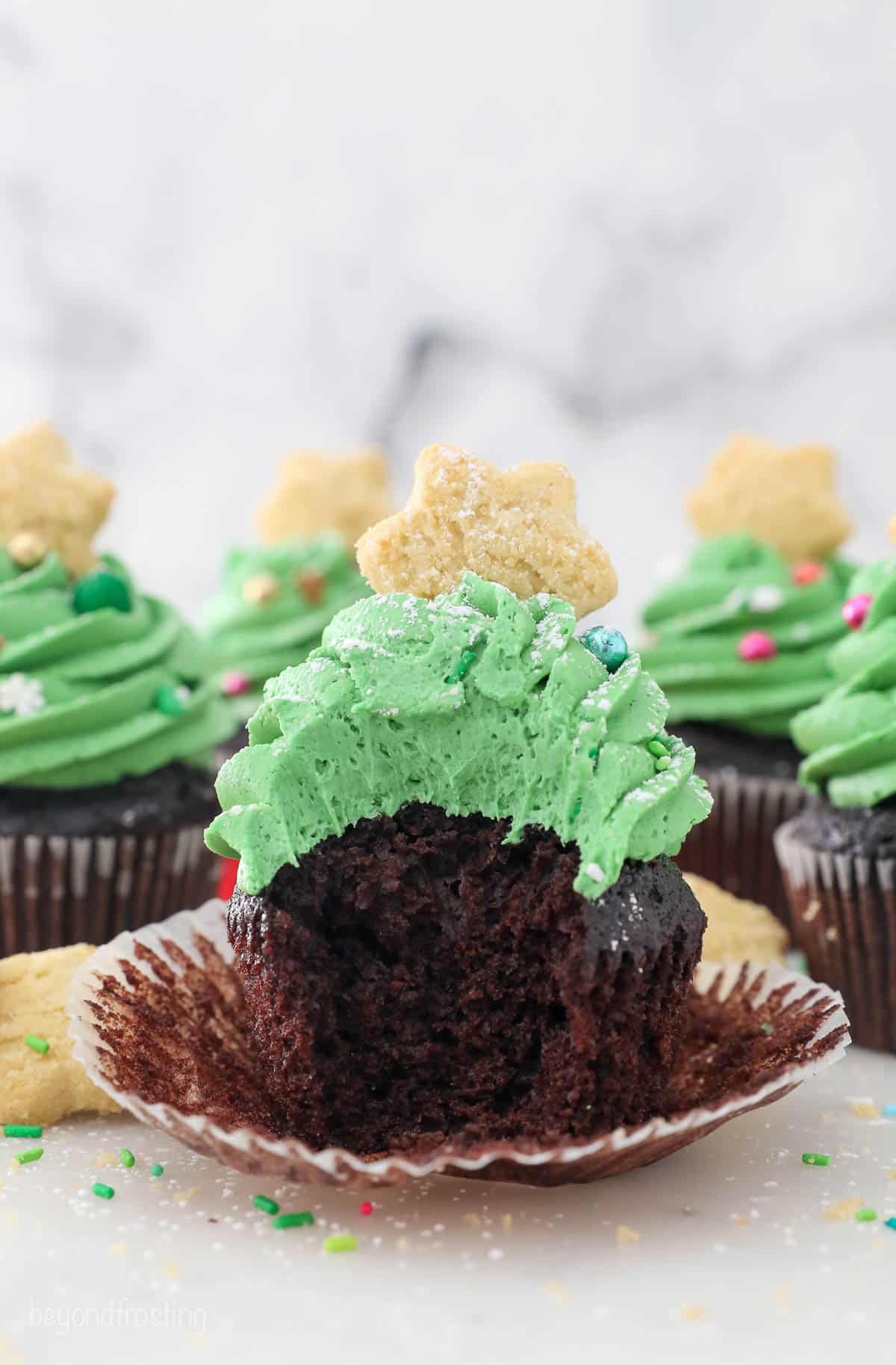 A Christmas tree cupcake, unwrapped with a bite removed
