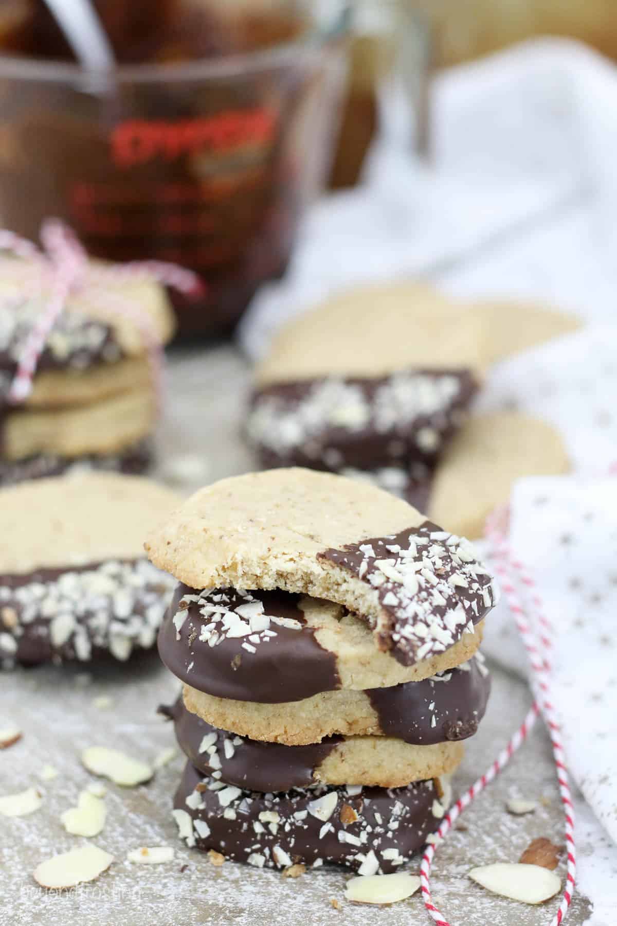 stack of shortbread cookies with more cookies and melted chocolate in the backgorund