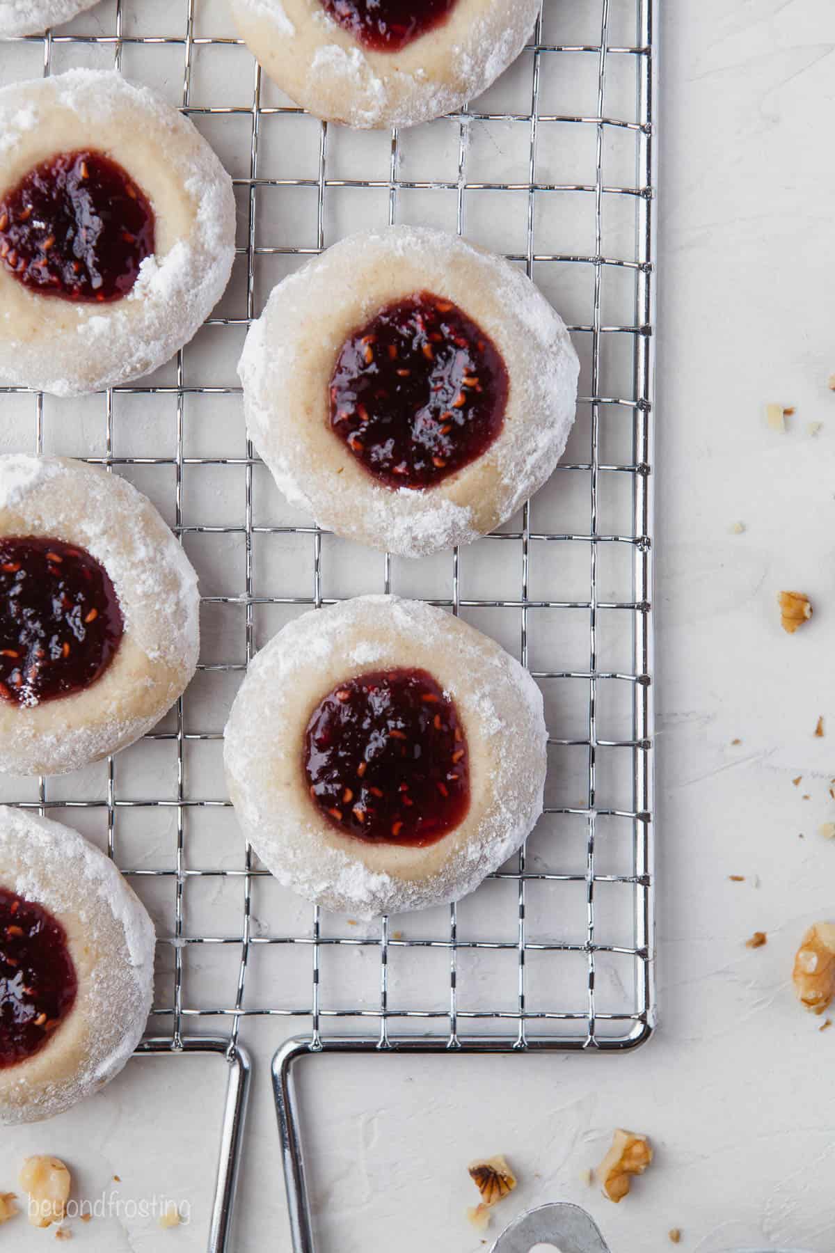 A bird's-eye view of jam-filled thumbprint cookies on a wire rack with a handle