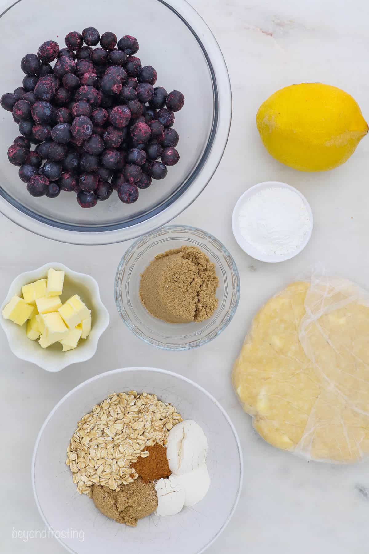 Ingredients for blueberry pie laid out on a marble table
