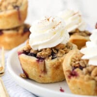 a close up of a small blueberry pie with whipped cream on a white rimmed plate