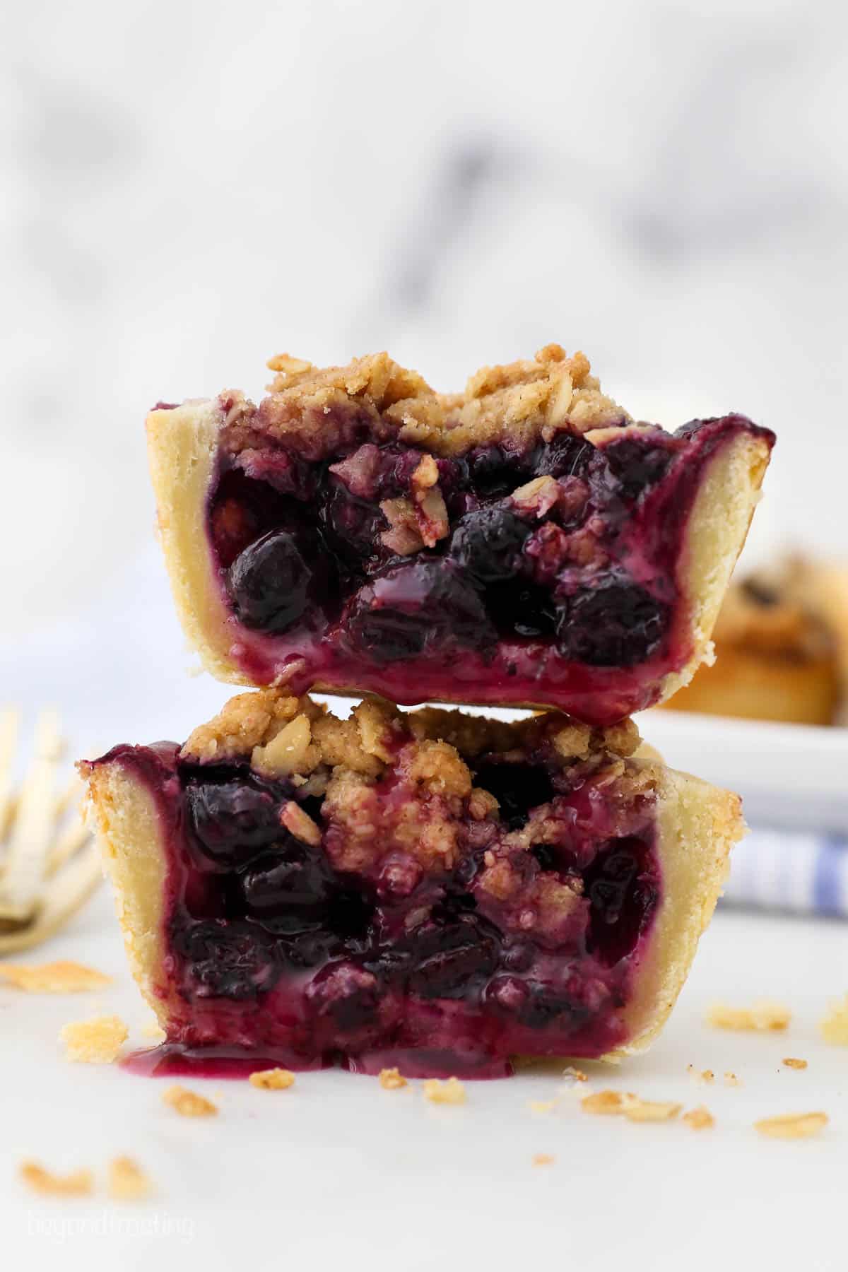 A mini blueberry pie cut in half to show the filling inside
