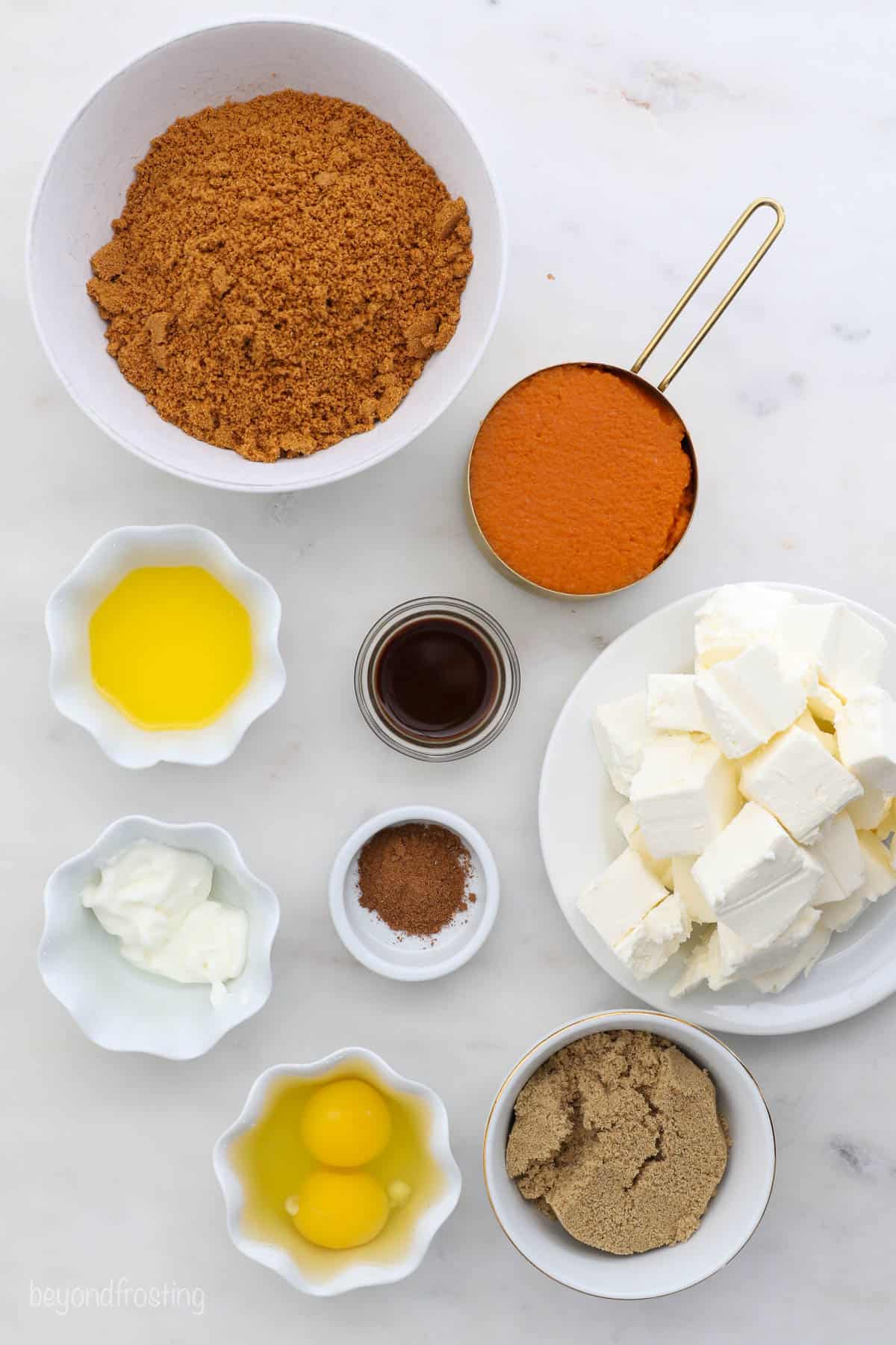 Ingredients for pumpkin cheesecake displayed in various bowls